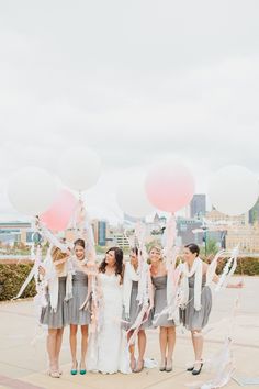 a group of women standing next to each other holding pink and white balloons in the air