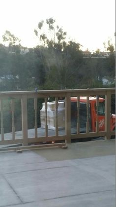 an orange truck parked on the side of a road next to a wooden fence and trees