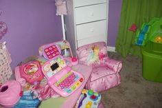 a pink toy laptop sitting on top of a table next to a chair and other toys