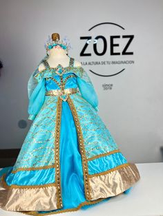 a blue and gold dress is displayed on a white table with the zoz logo in the background