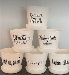 six white bowls with black lettering on them are stacked up in the shape of words