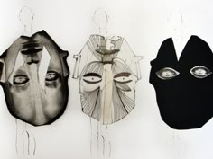 three masks are hanging on the wall next to each other, one is black and one is white