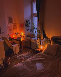 a room with a bed, desk and candles on the wall next to it in front of a window