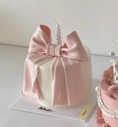 two cakes decorated with pink and white icing, one has a tiara on top