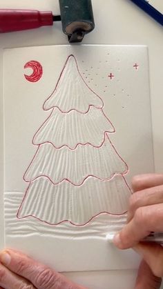 someone is drawing a christmas tree on a piece of paper