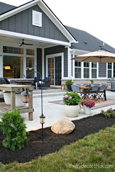 a patio with an umbrella and chairs in front of the house on a cloudy day