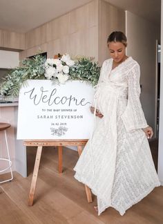 a pregnant woman standing next to a welcome sign