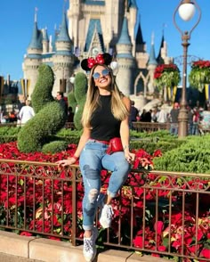 a woman in mickey mouse ears poses for a photo at the disneyland world park with her hand on her hip