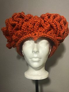 an orange crocheted hat on top of a mannequin's head