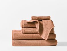 four folded towels stacked on top of each other in different shades of pink and orange