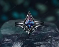 a ring with a blue topazte surrounded by black diamond accents on a rock