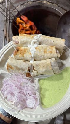 some food is on a white plate with onions and sauces next to the pita bread