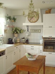 a kitchen with white cabinets and wooden table in front of the stove, sink and oven