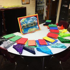 the table is covered with many different colored pieces of cloths and paper on it