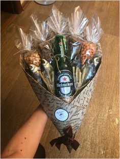 a bouquet of snacks and beer wrapped in cellophane with someone's hand