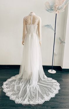 a wedding dress is displayed on a mannequin in front of a white flower