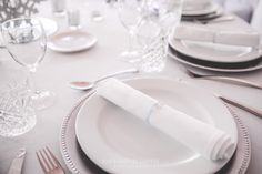 the table is set with white plates and silverware