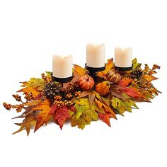 three candles are sitting on top of some autumn leaves