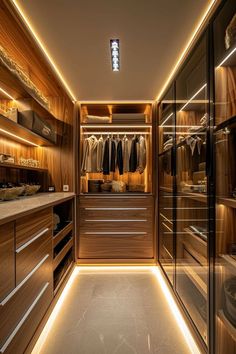 a walk - in closet with wooden cabinets and drawers is lit by recessed lights