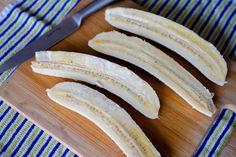 peeled bananas sitting on top of a cutting board next to a knife and blue striped napkin