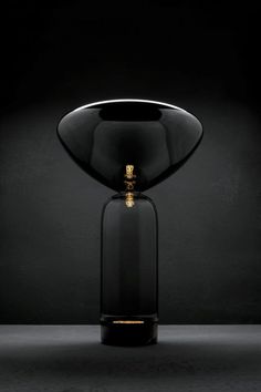 a black vase with a gold decoration on the top and bottom, sitting in front of a dark background