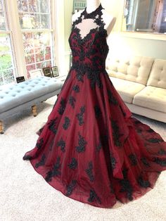 a red and black dress on display in front of a couch with a white sofa behind it