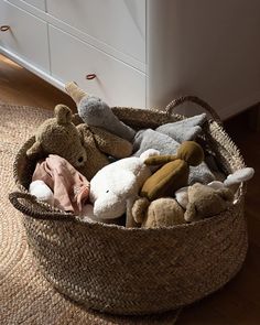 a basket filled with stuffed animals on top of a wooden floor