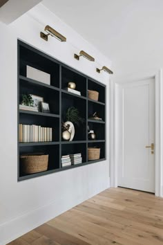 an empty room with black bookshelves and baskets on the shelves in front of it