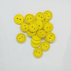 several yellow buttons with holes in them on a white surface