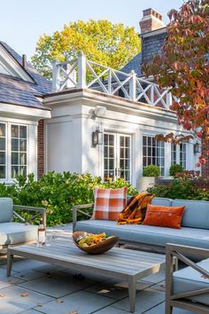 an outdoor living area with couches, tables and chairs in front of a house