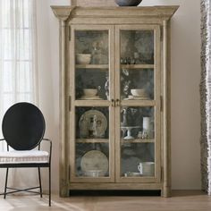 an old china cabinet with glass doors and dishes on it's shelves in a living room