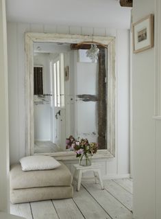 a white bathroom with wooden floors and a large mirror