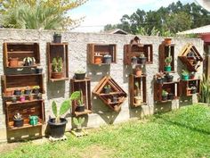 several wooden shelves filled with pots and plants on the side of a wall in front of a house