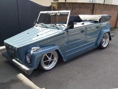 an old blue car parked in front of a building