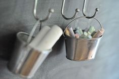 two metal buckets with pencils hanging from hooks