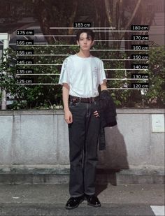 a young man standing in front of a building with measurements for his pants and shirt