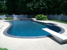 an empty swimming pool in the middle of a yard with lawn chairs and trees behind it