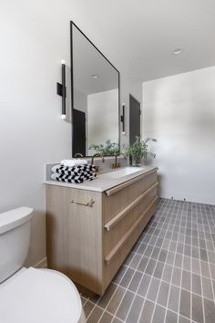 a bathroom with a sink, mirror, toilet and tiled flooring in the room