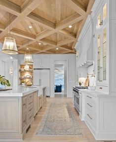 a large kitchen with white cabinets and wood ceilinging, along with an area rug on the floor