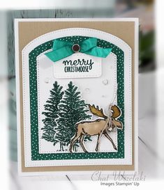 a close up of a christmas card with a deer and trees in the background on a table