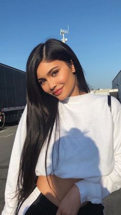 a woman with long black hair posing for the camera