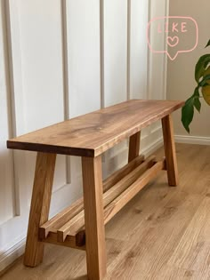 a wooden bench sitting on top of a hard wood floor next to a potted plant