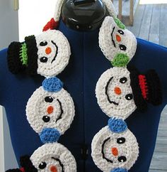 a crocheted snowman scarf hanging on a mannequin