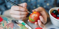 a person painting an egg with flowers on it