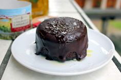 a piece of chocolate cake sitting on top of a white plate next to a jar of peanut butter