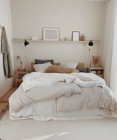 an unmade bed with white sheets and pillows in a bedroom next to a window