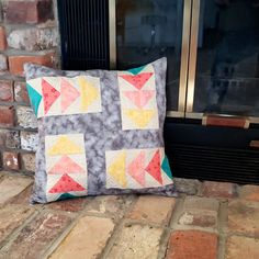 a pillow sitting on top of a brick floor next to a fire place with a window in the background