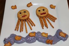 two cookies with faces made out of doughnuts on a white plate next to other food items