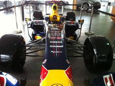 a red, yellow and blue race car is parked in a showroom with other cars