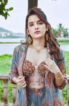 a woman in a colorful dress and jacket posing for the camera with her hand on her hip